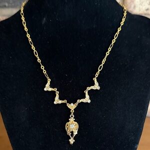 Gold tone necklace with rhinestone detail and raised pendant